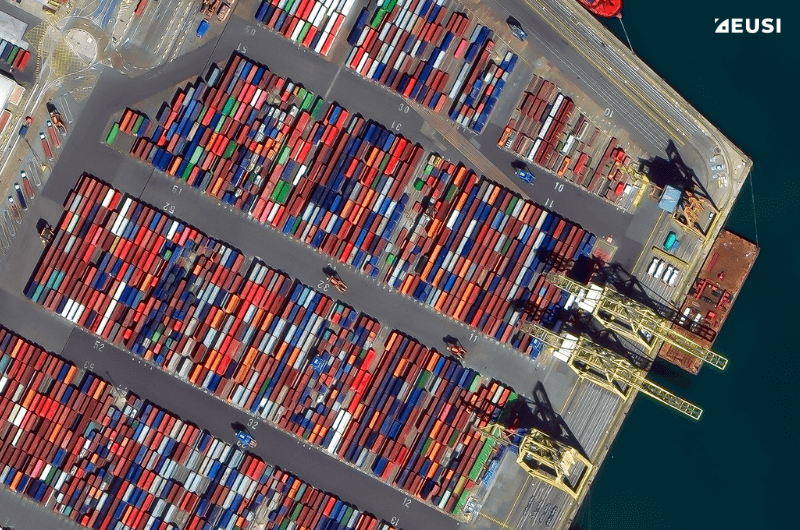 Satellite image of a port with cranes, containers and vehicles